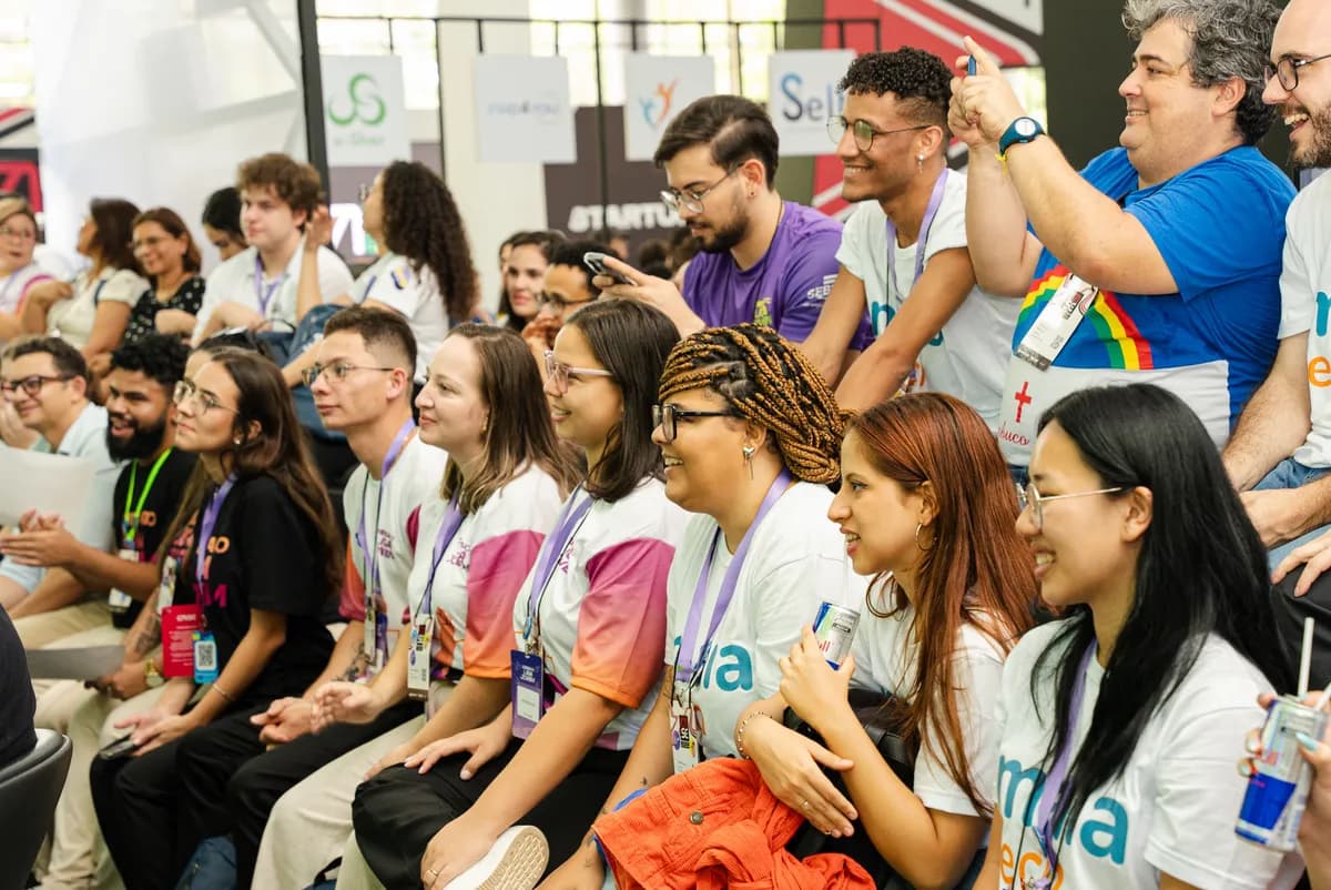 Estudantes e educadores sorrindo juntos na plateia de um evento do Instituto Ideias do Futuro.