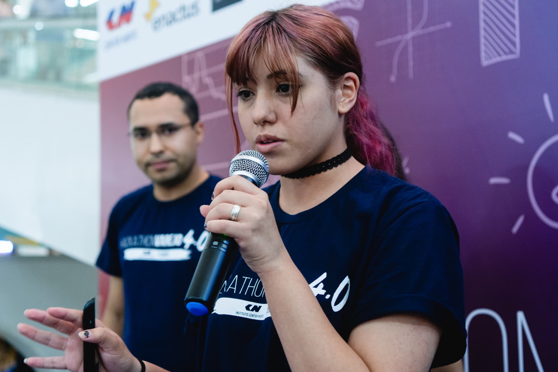 Letícia falando ao microfone durante um hackathon.